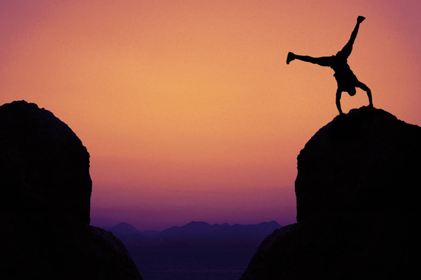 Silueta de gimnasta deportiva en las montañas como símbolo de diversión al aire libre al atardecer
 - Foto, imagen