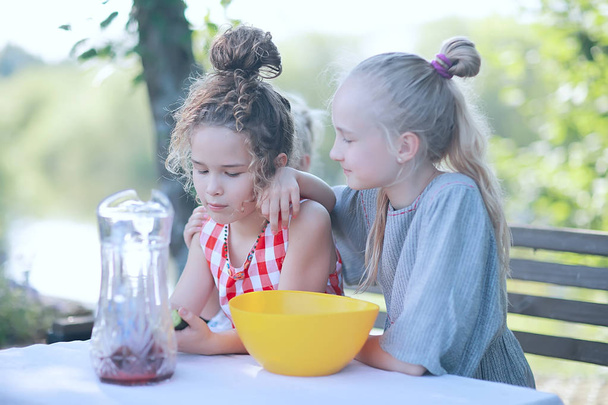 happy little girls sitting at table in summer garden - Foto, Imagem