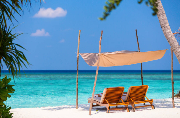 モルディブの美しい熱帯のビーチに木製ラウンジ椅子 - 写真・画像