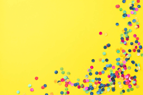 Flatlay of yellow background with colourful paper confetti in the corner and with copyspace - Фото, зображення