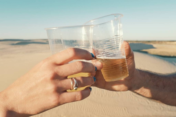 Santa Cruz w Boliwii - 5 września 2018 r.: młoda kobieta i mężczyzna brzęk plastikowych szklankach piwa na pustyni - Zdjęcie, obraz