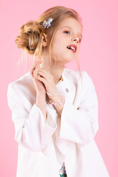 A teenage girl in light clothes posing on a pink background. - Photo, Image