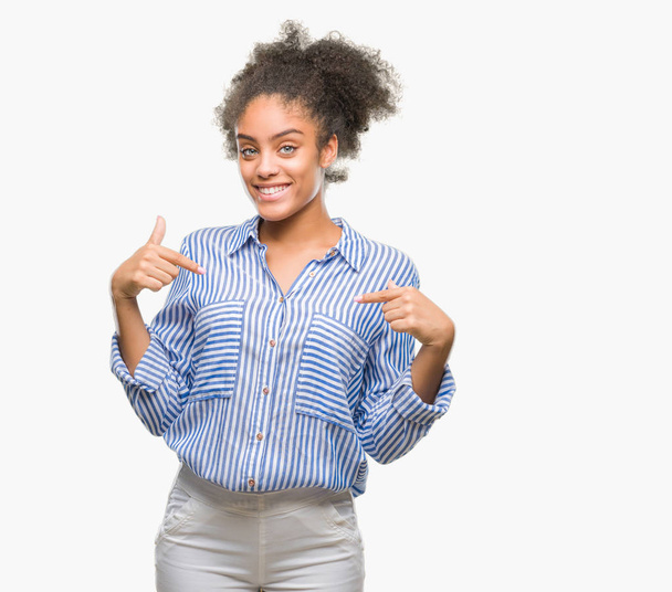 Młody afro american kobieta na białym tle patrząc pewny siebie z uśmiechem na twarzy, wskazując siebie palcami, dumny i szczęśliwy. - Zdjęcie, obraz
