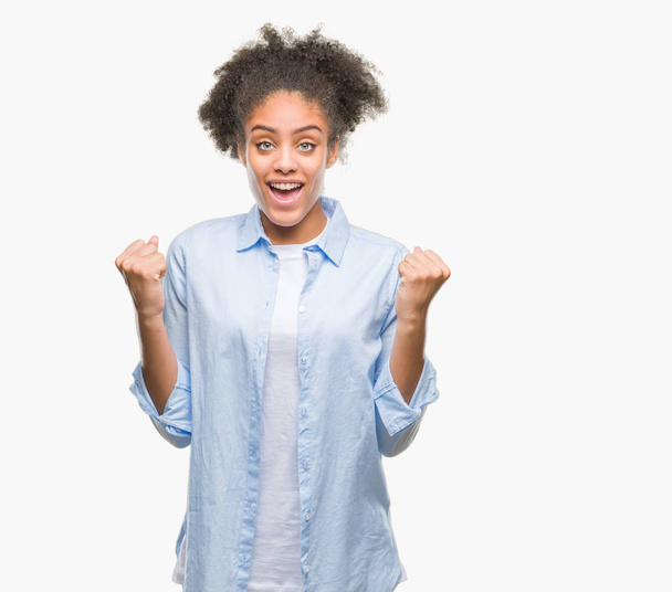 Jonge afro-Amerikaanse vrouw over geïsoleerde achtergrond vieren verrast en verbaasd voor succes met armen aan de orde gesteld en ogen open. Winnaar concept. - Foto, afbeelding