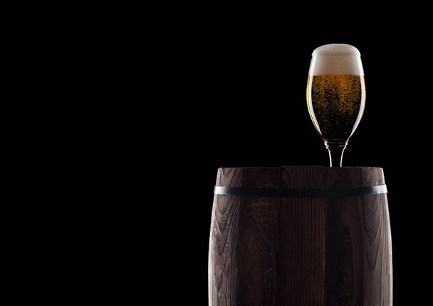 Cold glass of craft beer on old wooden barrel on black background with dew and bubbles. With space for your text. - Photo, Image
