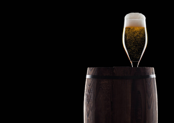 Cold glass of craft beer on old wooden barrel on black background with dew and bubbles. With space for your text. - Fotografie, Obrázek