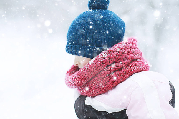 cute little girl in snowy winter park, seasonal photo of a child in warm clothes - 写真・画像