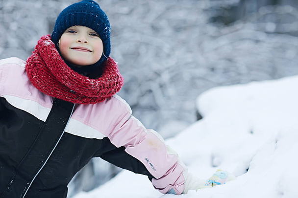cheerful happy little girl on winter walk. The concept of  happy childhood. Warm sportswear down jacket - Photo, image