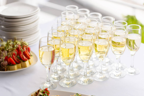 Cantinero vertiendo champán o vino en copas de vino sobre la mesa en el restaurante. solemne ceremonia de boda o feliz año nuevo banquete
 - Foto, imagen