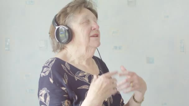 Active Senior caucasian woman listening and singing to music on MP3 player at home on headphones  - Záběry, video
