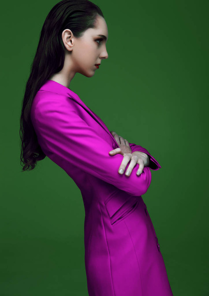 Fashion model with wet hair wearing violet purple long coat on green background. Fashion portrait. - Foto, afbeelding