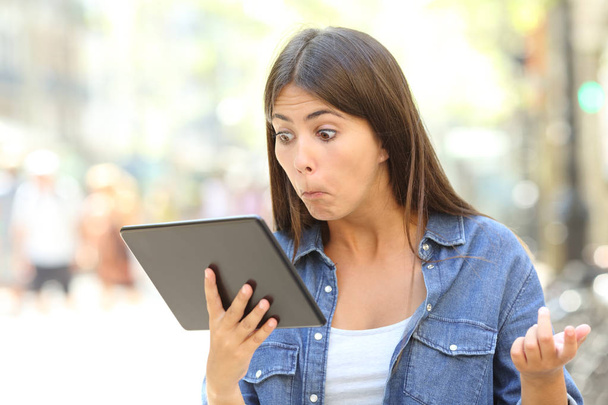 Összezavarodott lány néz a sor tartalmát egy tabletta, kint az utcán - Fotó, kép