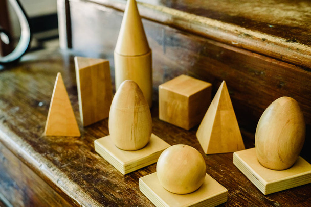 Formas de madera maciza para estudiar geometría y volúmenes, conos, triángulos, cuadrados, esferas sobre un fondo de madera caliente
. - Foto, imagen