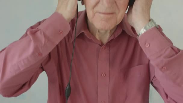 Active Senior caucasian man listening and singing to music on MP3 player at home on headphones  - Кадры, видео