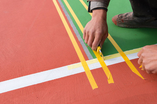 werknemers taping en markering van de zijlijn op de vloer voor een openlucht stadion - Foto, afbeelding