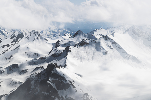 Vista panorâmica de picos de alta montanha em tempo frio nevado e nebuloso, região de Elbrus
 - Foto, Imagem