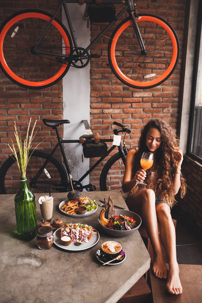 Γυναίκα απολαμβάνοντας φρέσκα βιολογικά τρόφιμα για χορτοφάγους και ποτήρι kombucha hipster στυλ καφέ - Φωτογραφία, εικόνα