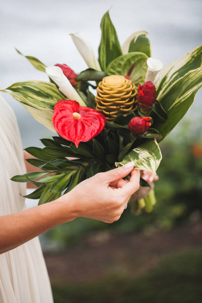 Bride holding bouquet with red and green tropical flowers  - Fotoğraf, Görsel