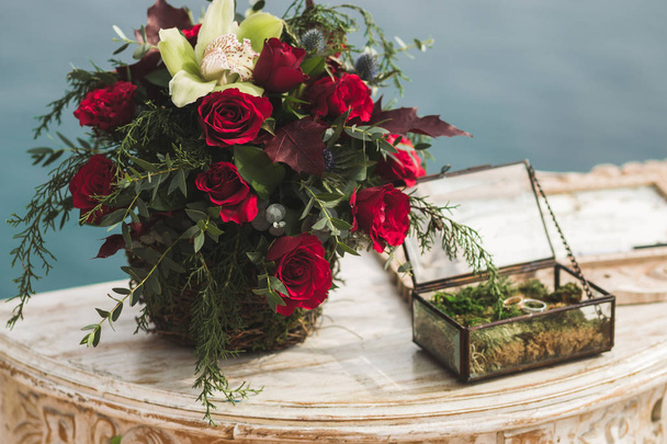 Kaksi kultaista vihkisormusta sammal vintage lasi laatikko koristeltu ruusut
 - Valokuva, kuva