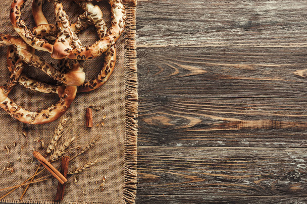 Rustic background, pretzels or bretzels and cinnamon sticks on wooden table. Concept of pastry, top view - Photo, Image