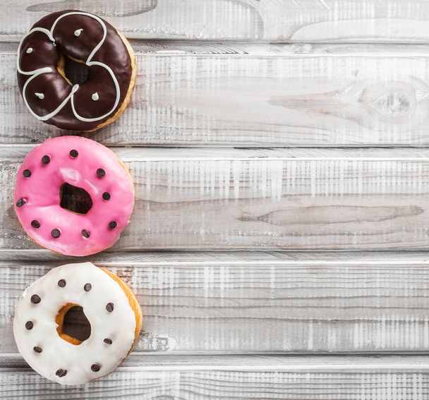 Three sweet donuts on an old wooden table. Selective focus, top view and copy space - Φωτογραφία, εικόνα