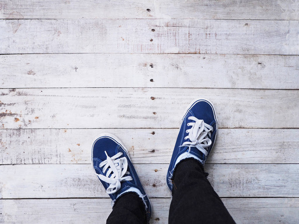Selfie hipster feet wearing blue sneakers on white wooden vintage floor background.  - Fotoğraf, Görsel