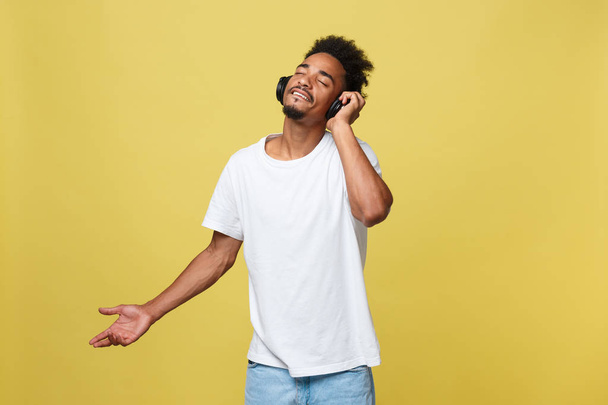 Молодий чорний чоловік слухає музику через навушники. Ізольовані на жовтому тлі
. - Фото, зображення