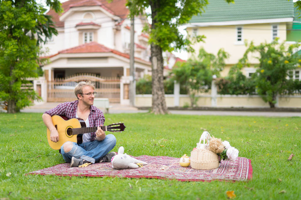 Retrato del hombre haciendo picnic mientras toca la guitarra al aire libre
 - Foto, Imagen
