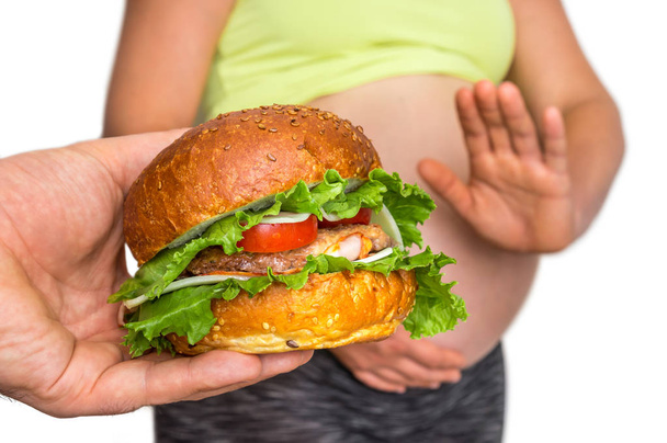 Pregnant woman with belly refused to eat a burger - unhealthy eating in pregnancy concept - Photo, image