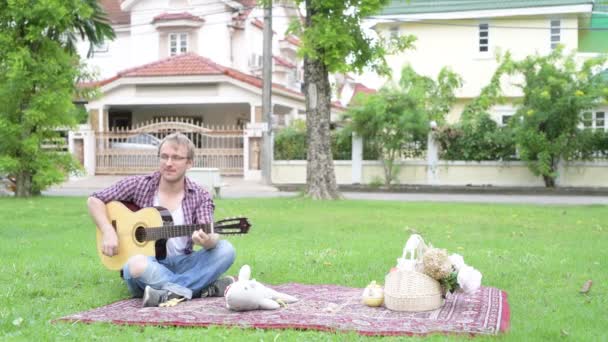 Retrato del hombre haciendo picnic mientras toca la guitarra al aire libre
 - Metraje, vídeo