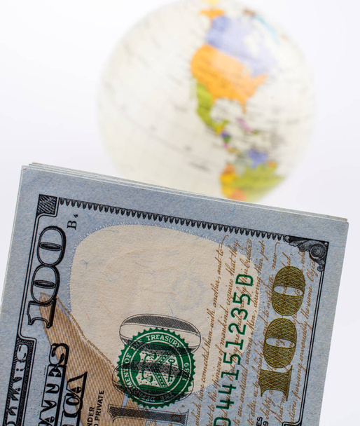 Billetes en dólares americanos al lado de un globo modelo sobre fondo blanco
 - Foto, Imagen