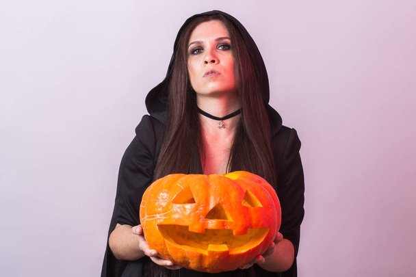 junge Frau im Halloween-Hexenkostüm im Atelier mit gelbem Kürbis. - Foto, Bild