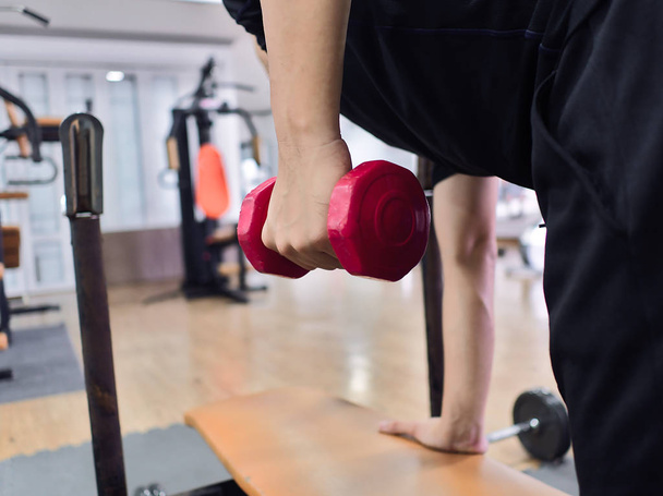 Fit jonge Aziatische man tillen halter bij sportschool. Fitness en workout concept - Foto, afbeelding