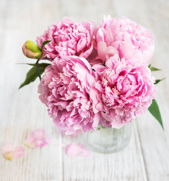 白い木製のテーブルの上にピンクの牡丹花と花瓶 - 写真・画像