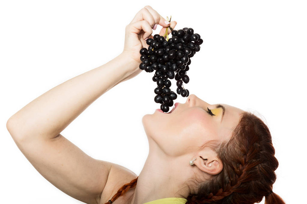 Beautiful redhead woman is eating black grapes. concept of healthy eating - 写真・画像