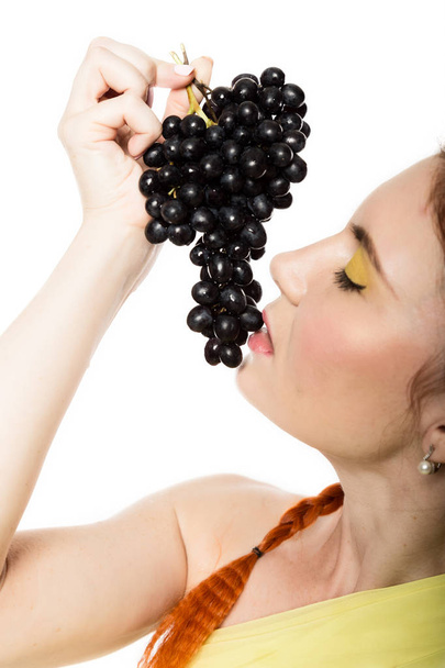 Beautiful redhead woman is eating black grapes. concept of healthy eating - Foto, Bild