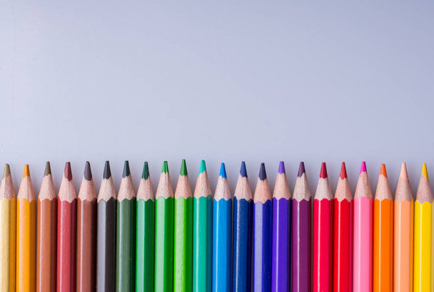 Kleurpotloden van verschillende kleuren geplaatst op witte achtergrond - Foto, afbeelding