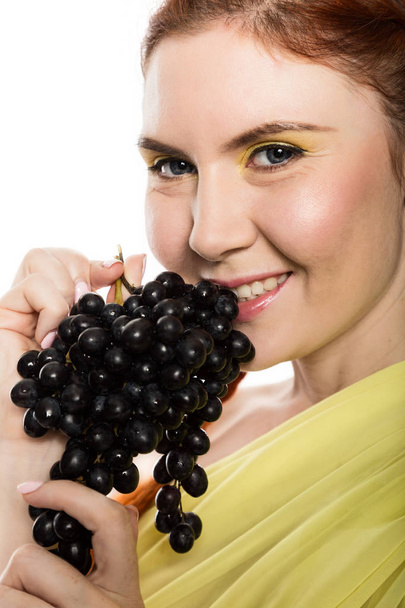 Beautiful redhead woman is eating black grapes. concept of healthy eating - Foto, Imagem