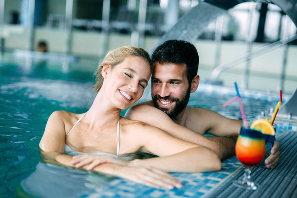 Happy attractive couple relaxing in spa swimming pool - Fotó, kép