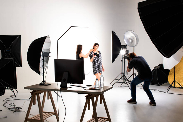 Photographe et mannequin travaillant dans un studio d'éclairage moderne avec de nombreux types de flash et accessoires
. - Photo, image
