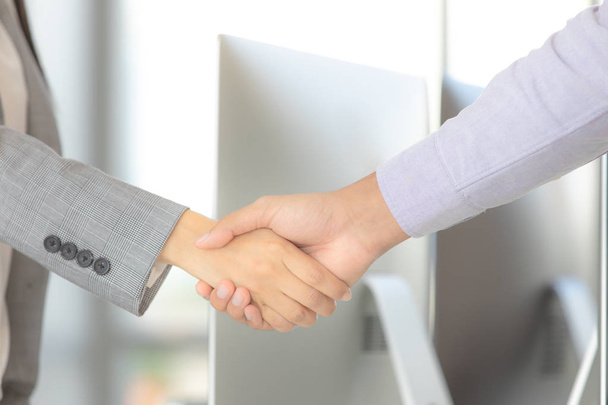 Zakenman en zakenvrouw schudden handen voor werk samen werk succesvol in moderne kantoor computer achtergrond. - Foto, afbeelding