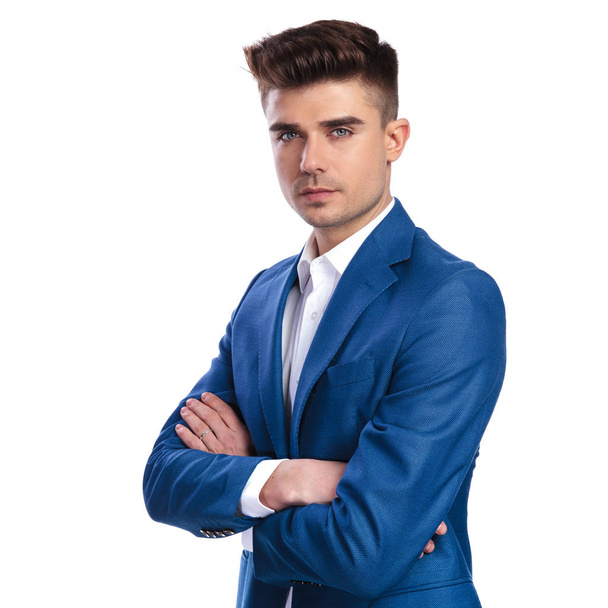 serious young businessman standing with hands crossed on white background - Photo, Image