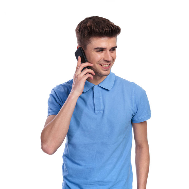 sorrindo homem casual falando no telefone olha para o lado no fundo branco
 - Foto, Imagem