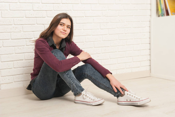 girl sitting on the floor against a brick wall - 写真・画像