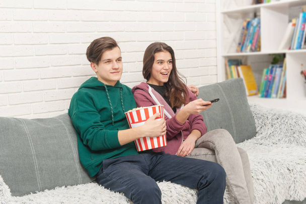 Two teenagers are sitting on the couch watching TV - 写真・画像