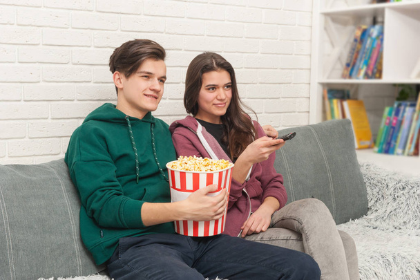 Two teenagers are sitting on the couch watching TV - Photo, Image