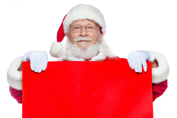 Weihnachten. Der freundliche Weihnachtsmann in weißen Handschuhen hält einen leeren roten Karton in der Hand. Platz für Werbung, für Text, leeren Raum. Copy-Paste. isoliert auf weißem Hintergrund. - Foto, Bild
