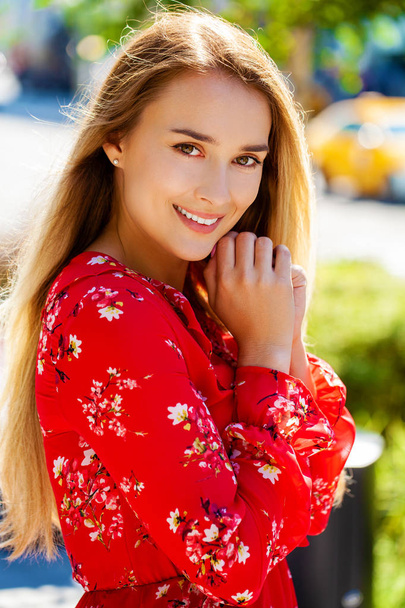 Portrait close up of young beautiful happy blonde woman in red dress, summer street outdoors - Photo, image