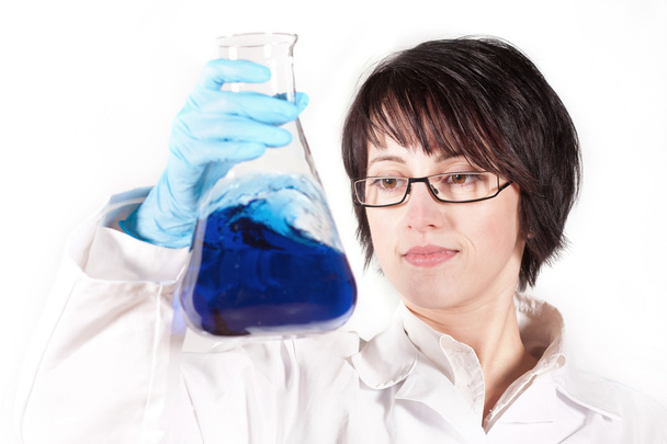 ένα θηλυκό επιστημονικός ερευνητής κοιτάζοντας ένα υγρό διάλυμα. - Φωτογραφία, εικόνα