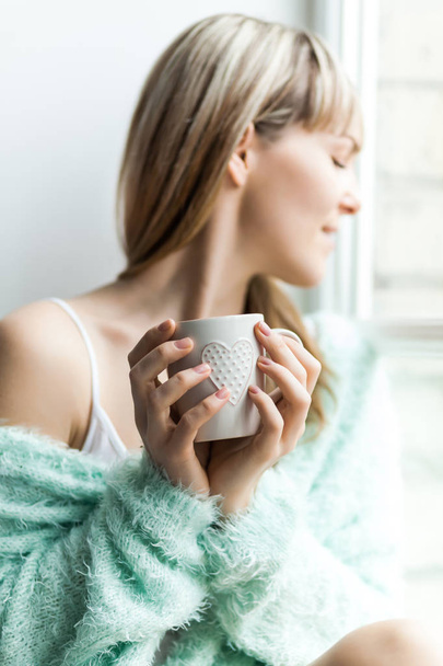 A gyönyörű nő reggel kávét iszik. Tavasz vagy őszi napkelte. Kávéscsésze. Ablak. Természetes gyapjú. - Fotó, kép